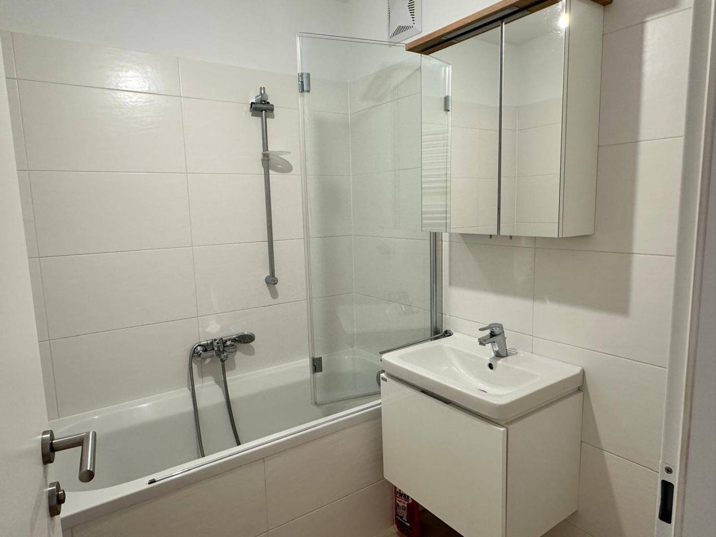 Modernes Badezimmer mit Badewanne, Duschabtrennung, Waschbecken und Spiegelschrank.