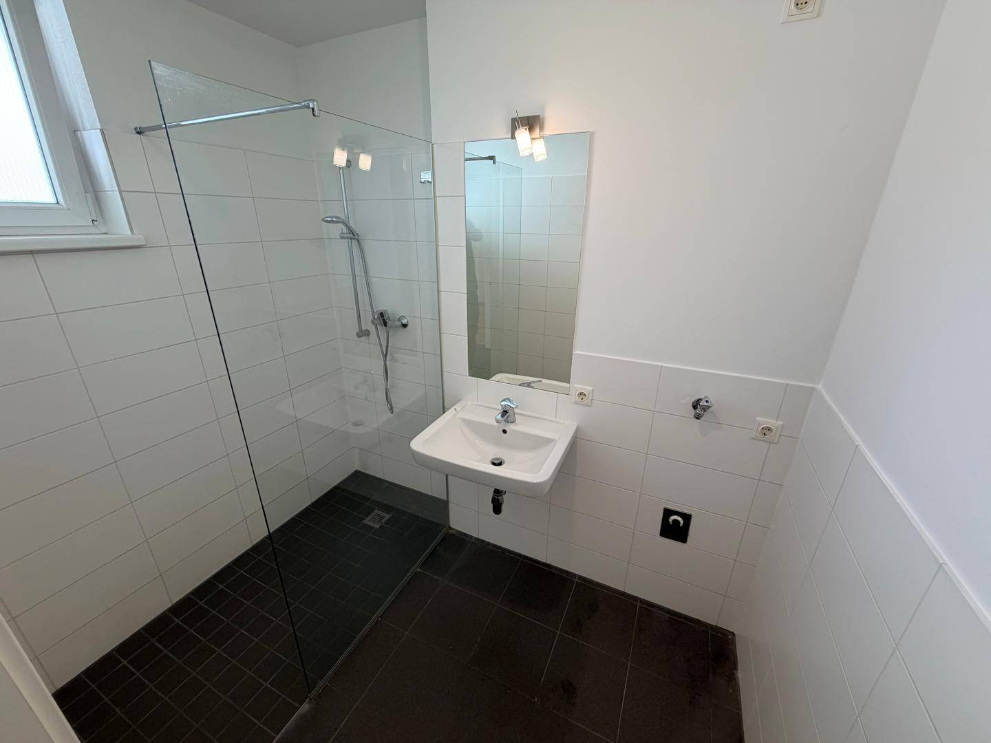 Modernes Badezimmer mit ebenerdiger Dusche, Waschbecken, Spiegel und Fenster.