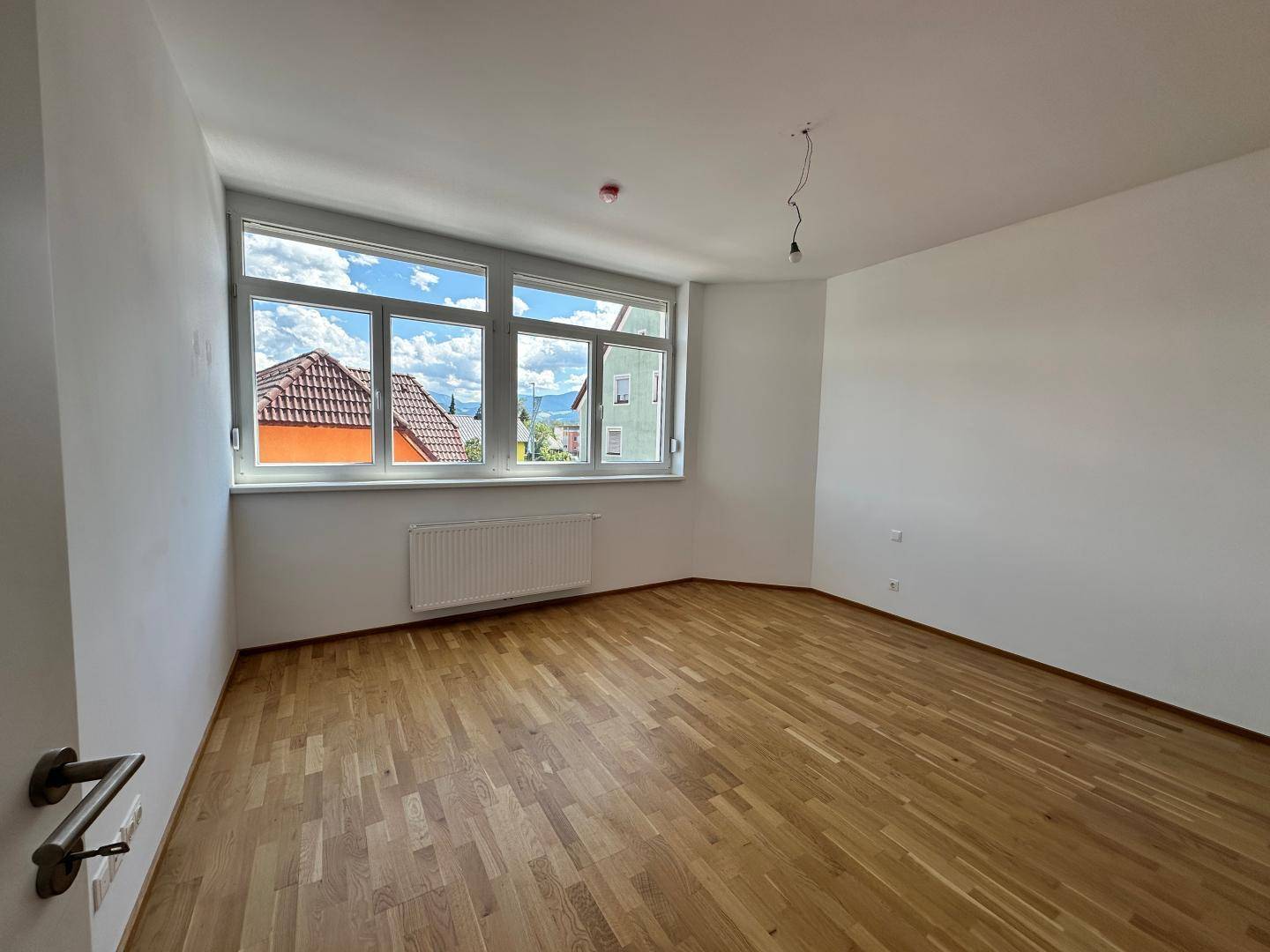 Geräumiges Schlafzimmer mit großen Fenstern, Parkettboden und viel Tageslicht.