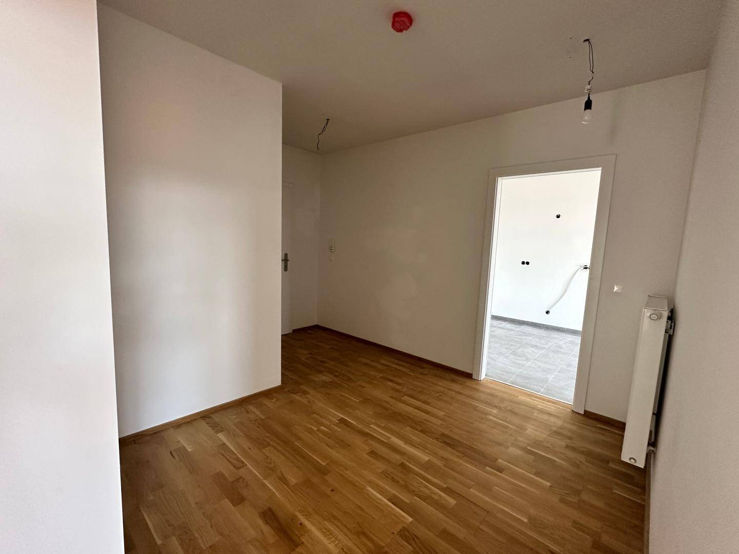 Unmöblierter Raum mit Parkettboden und einem gefliesten Bereich, ideal als Schlafzimmer.
