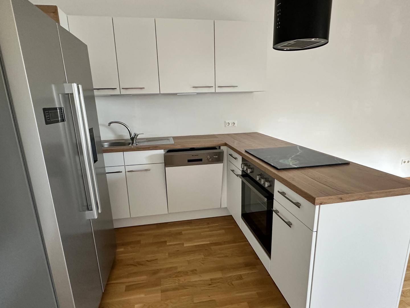 Moderne Einbauküche mit integriertem Backofen, Induktionskochfeld, Spüle und Geschirrspüler.