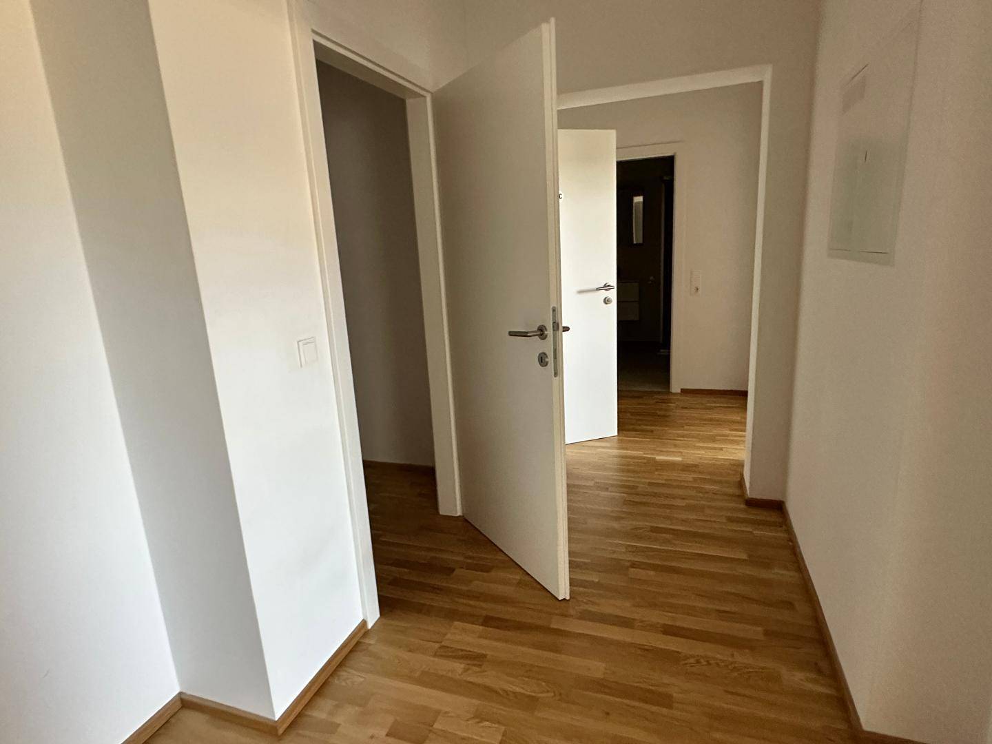 Heller Flur mit Parkettboden und mehreren weißen Türen, die zu den angrenzenden Räumen führen.