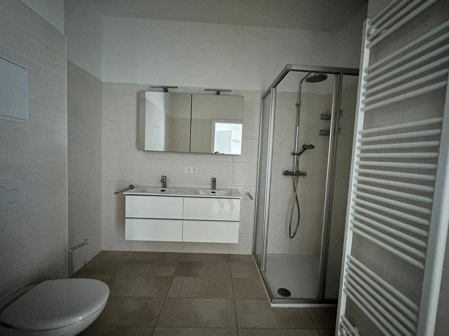 Geräumiges Badezimmer mit moderner Ausstattung, Doppelwaschbecken, Duschkabine und Wand-WC.
