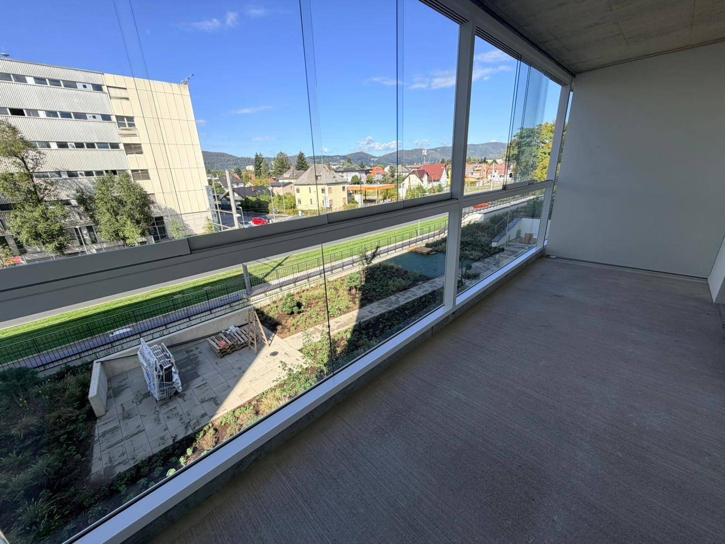 Weitläufige Loggia mit Glasfront und Ausblick auf die Stadt und die umliegende Landschaft.