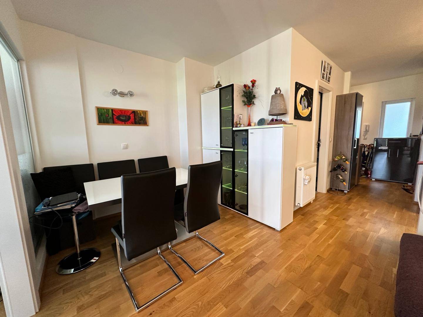 Essbereich mit dunkler Sitzbank, Esstisch und beleuchteter Vitrine.