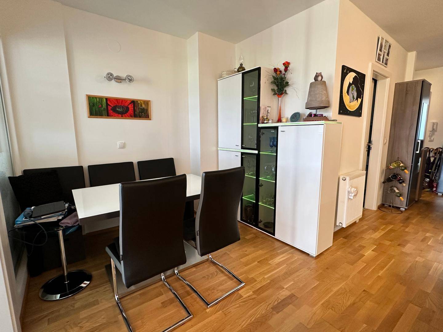Heller Essbereich mit modernem Tisch, Stühlen und beleuchteter Vitrine.