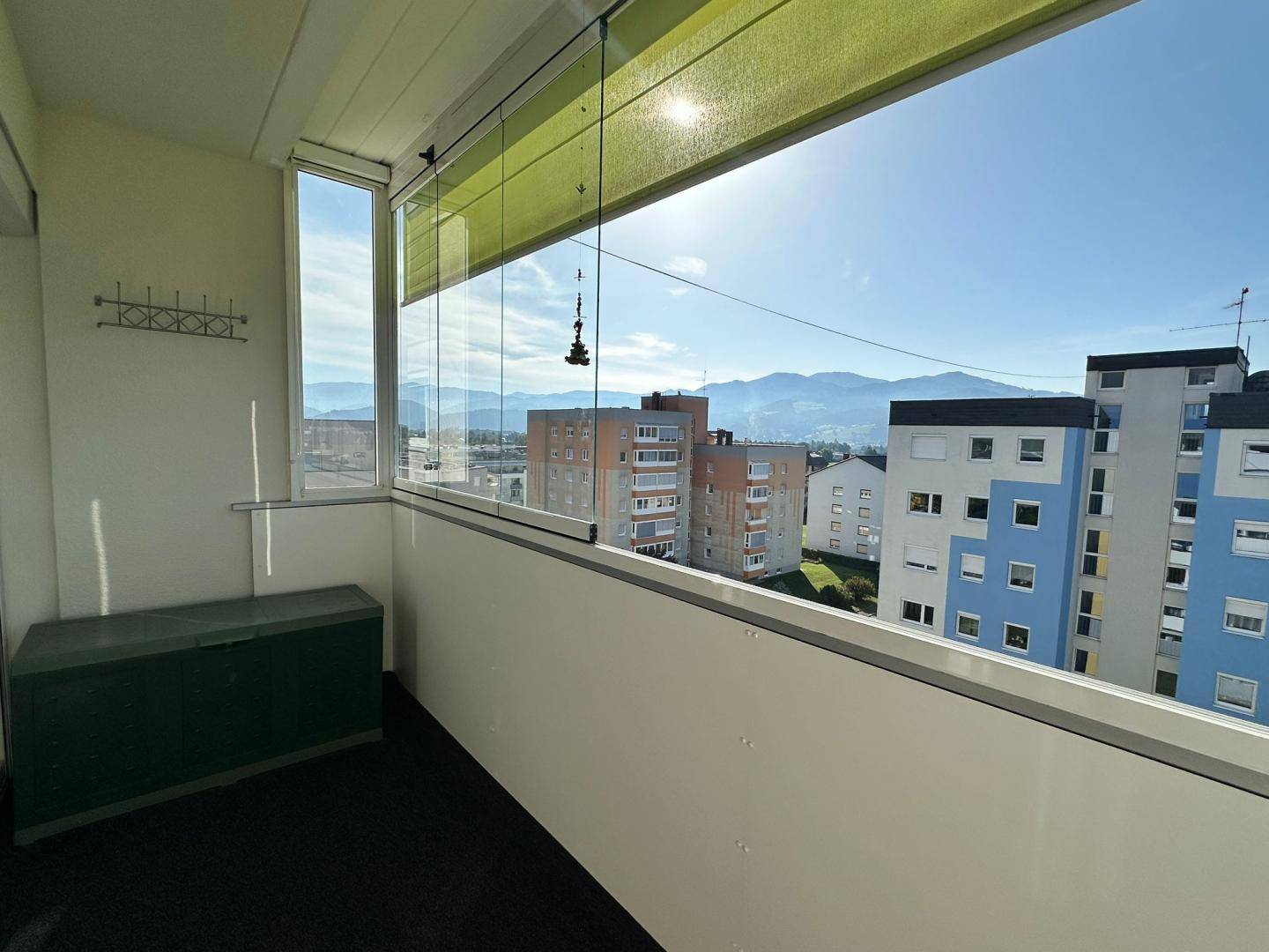 Verglaster Balkon mit Panoramablick auf die Berge und die umliegende Bebauung.