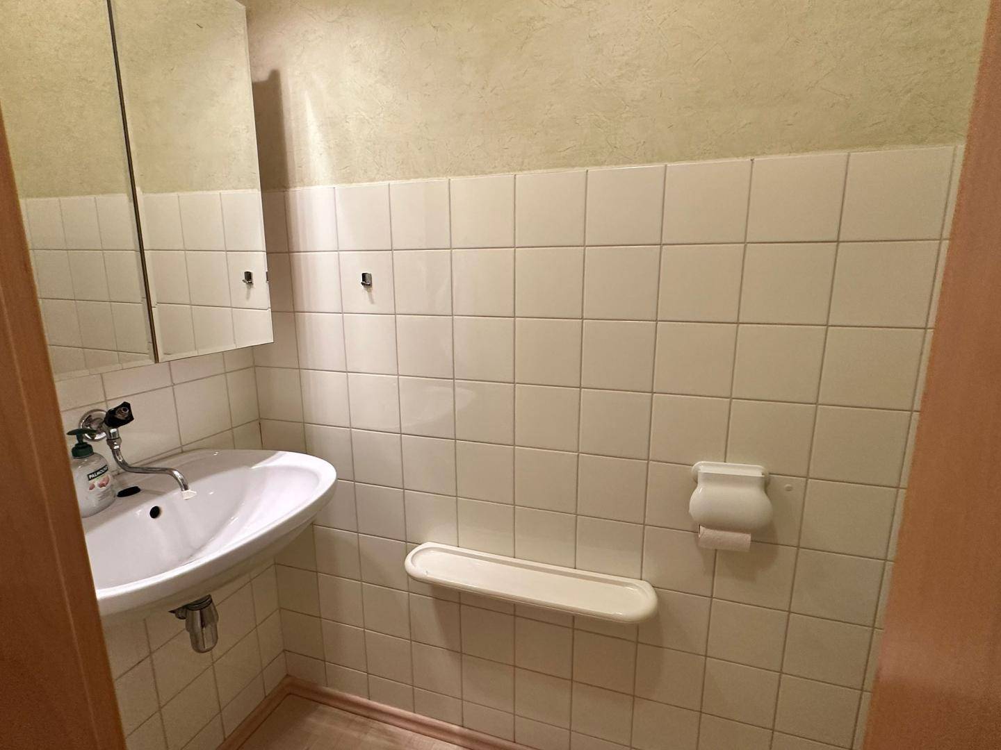 Gäste-WC mit Waschbecken und weißen Fliesen an den Wänden.
