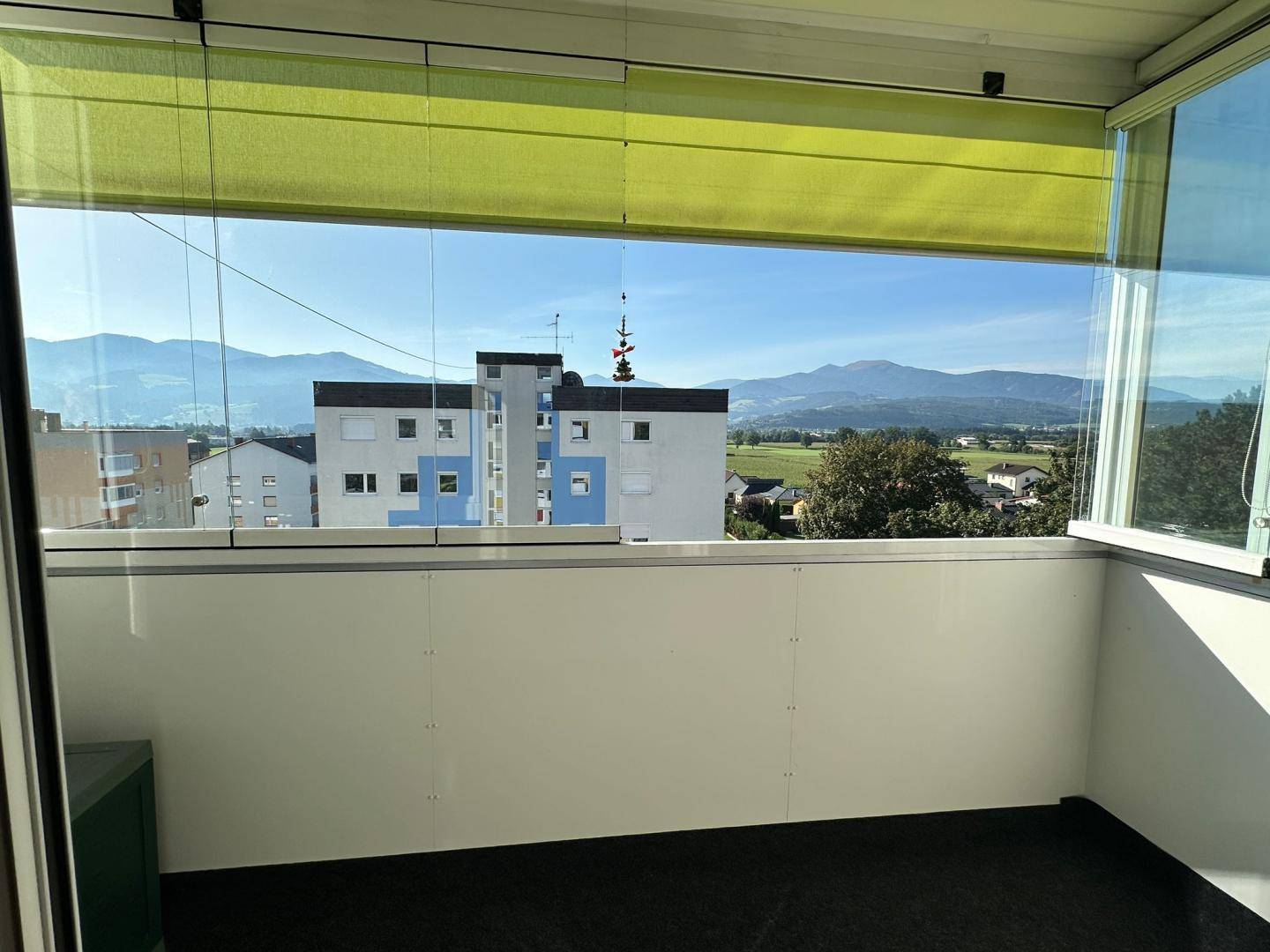 Heller, verglaster Balkon mit weitem Blick auf die Berge und die Stadt.