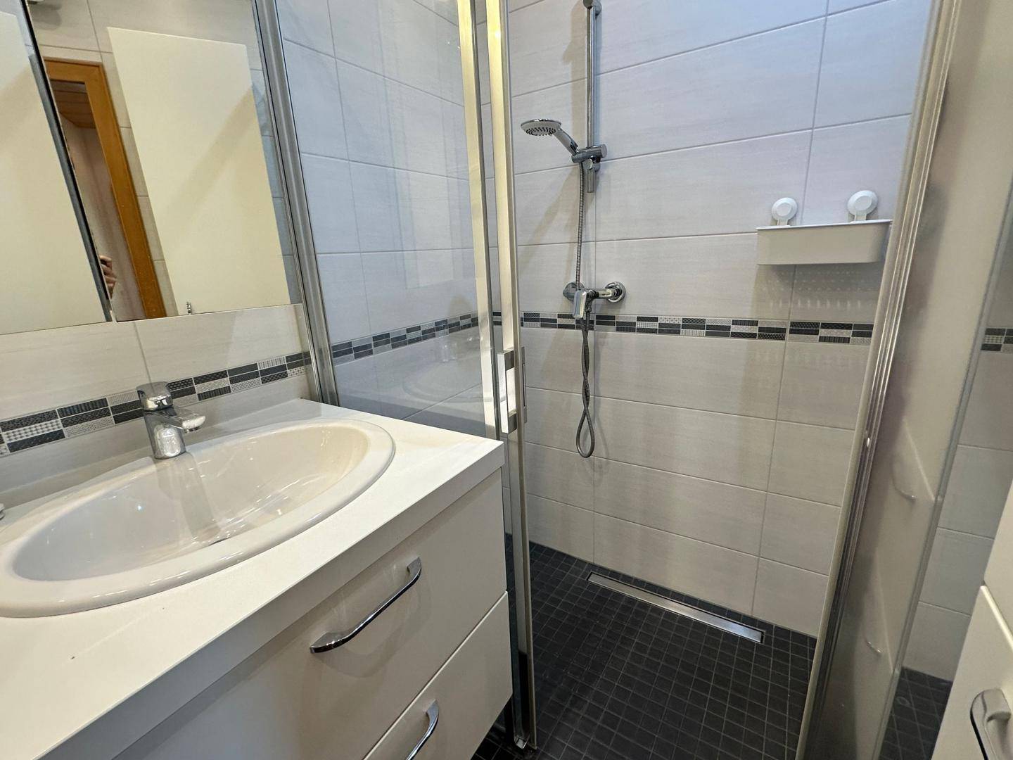 Duschbereich im Badezimmer mit modernen Fliesen und einer Glasduschwand für ein offenes Gefühl.