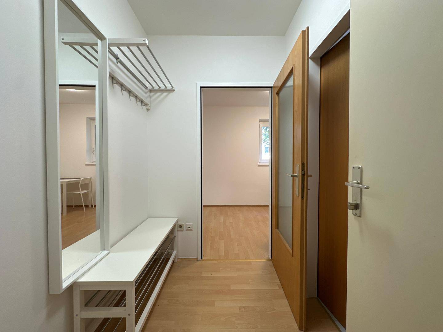 Heller Flur mit Garderobe, Spiegel und Sitzbank, der zu den weiteren Wohnbereichen führt.