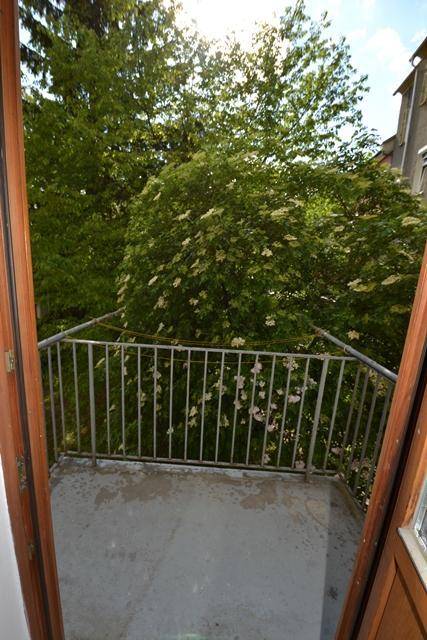 Kleiner Balkon mit Blick ins Grüne und auf blühende Bäume.