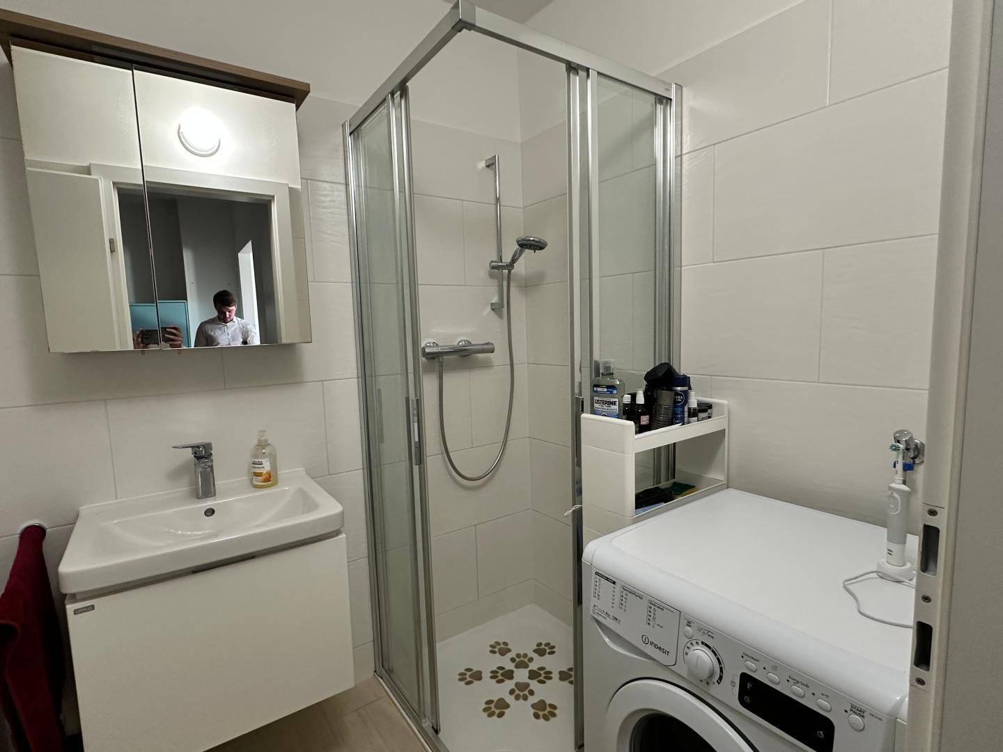 Modernes Badezimmer mit Dusche, Waschbecken und integrierter Waschmaschine.