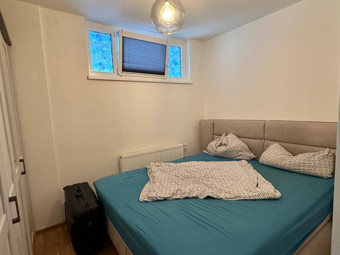 Schlafzimmer mit Doppelbett, Kleiderschrank und kleinem Fenster.