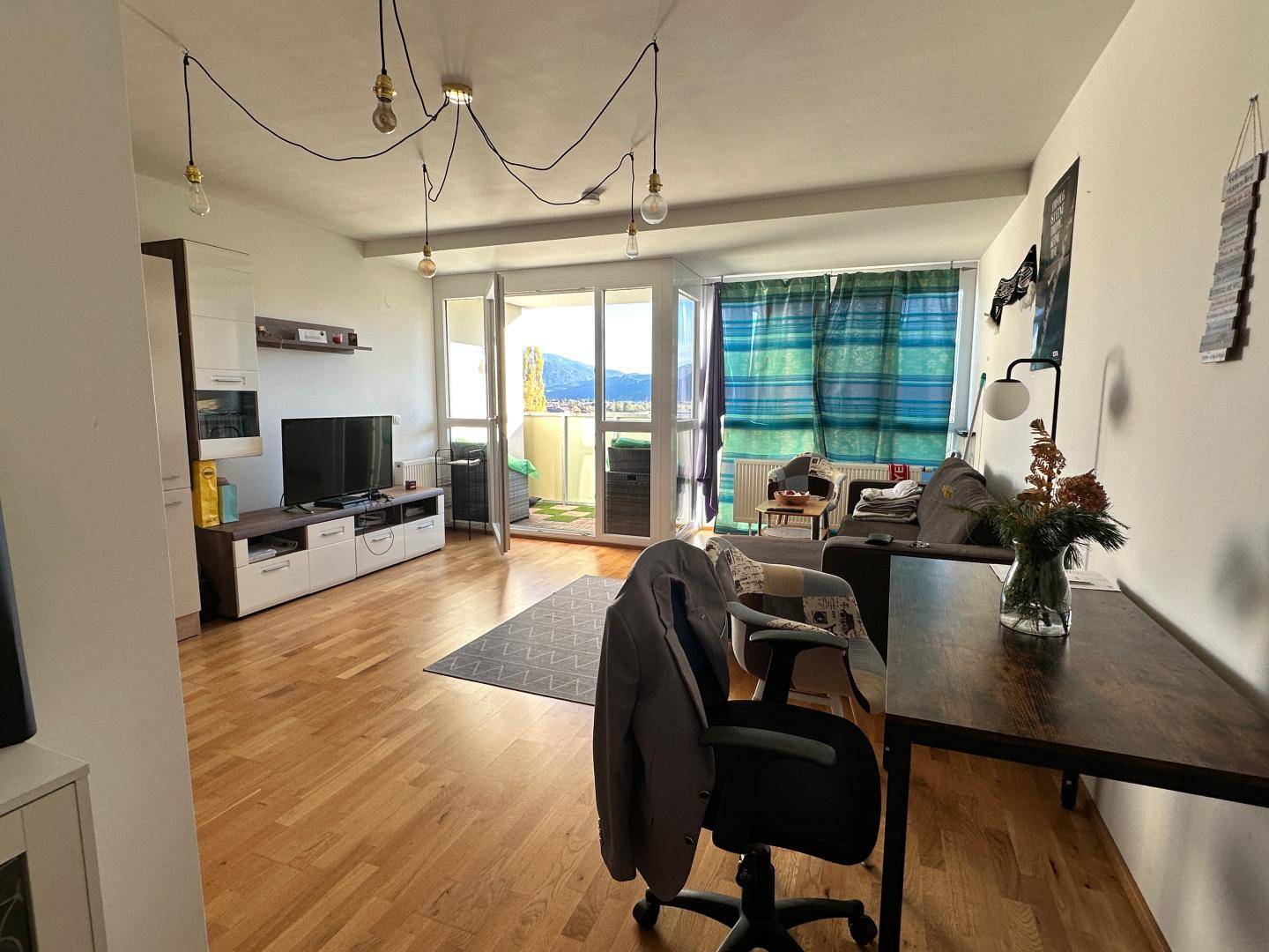 Helles Wohnzimmer mit Zugang zum Balkon und Blick auf die umliegende Landschaft.