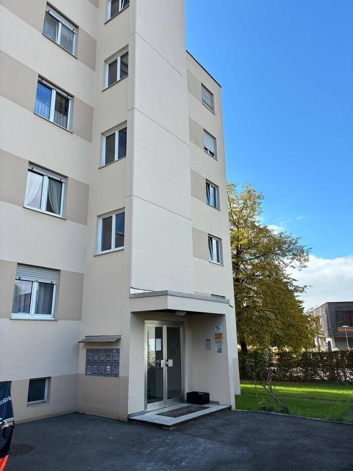 Ansicht der modernen Fassade eines Mehrfamilienhauses mit Eingangsbereich und Briefkästen.