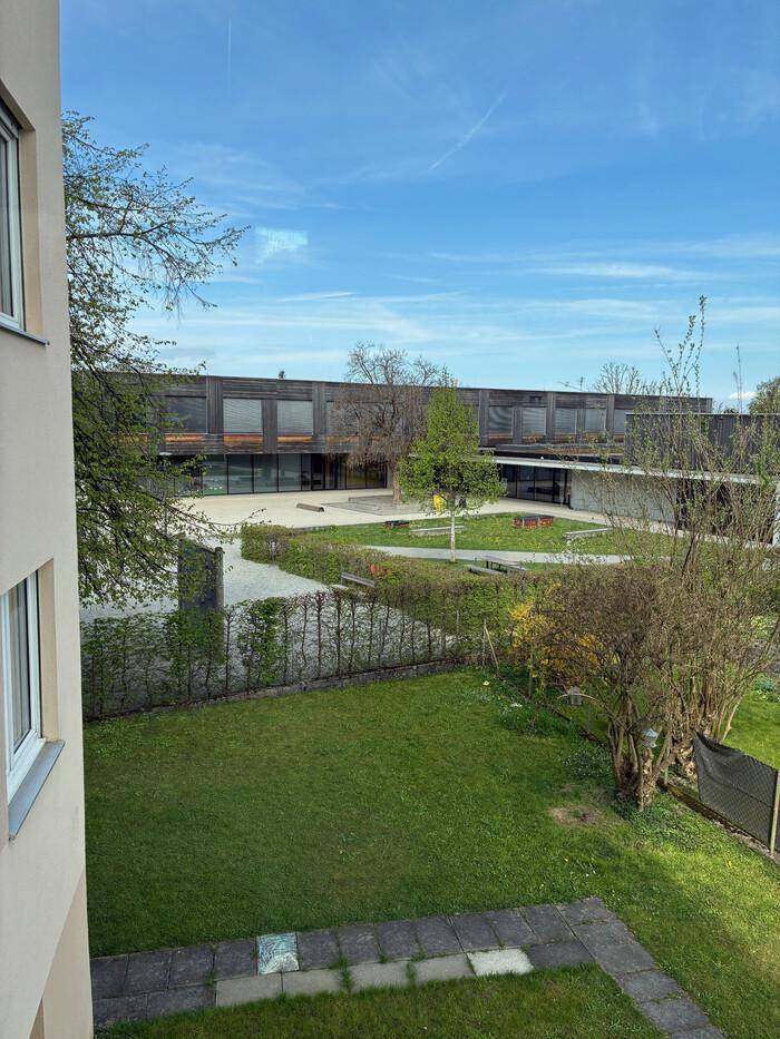 Weitläufiger Blick auf ein modernes Gebäude mit großer Grünfläche und Teichanlage.