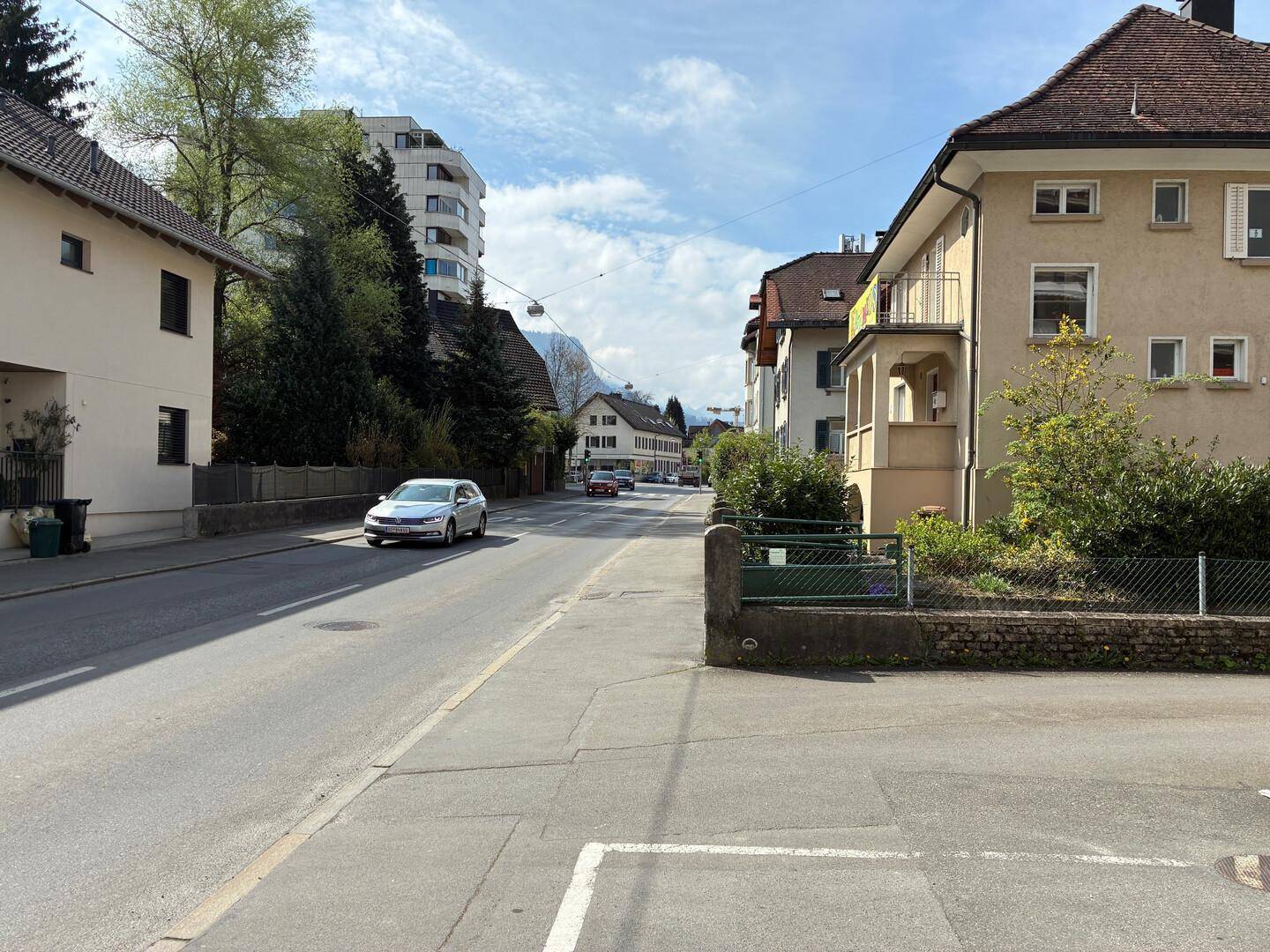 Blick auf eine ruhige Wohnstraße mit gepflegten Häusern und parkenden Autos.
