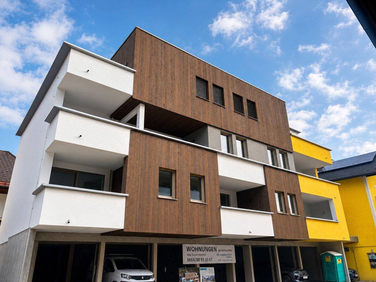 Außenansicht des Neubaus mit markanter Holzfassade und modernen Balkonen.