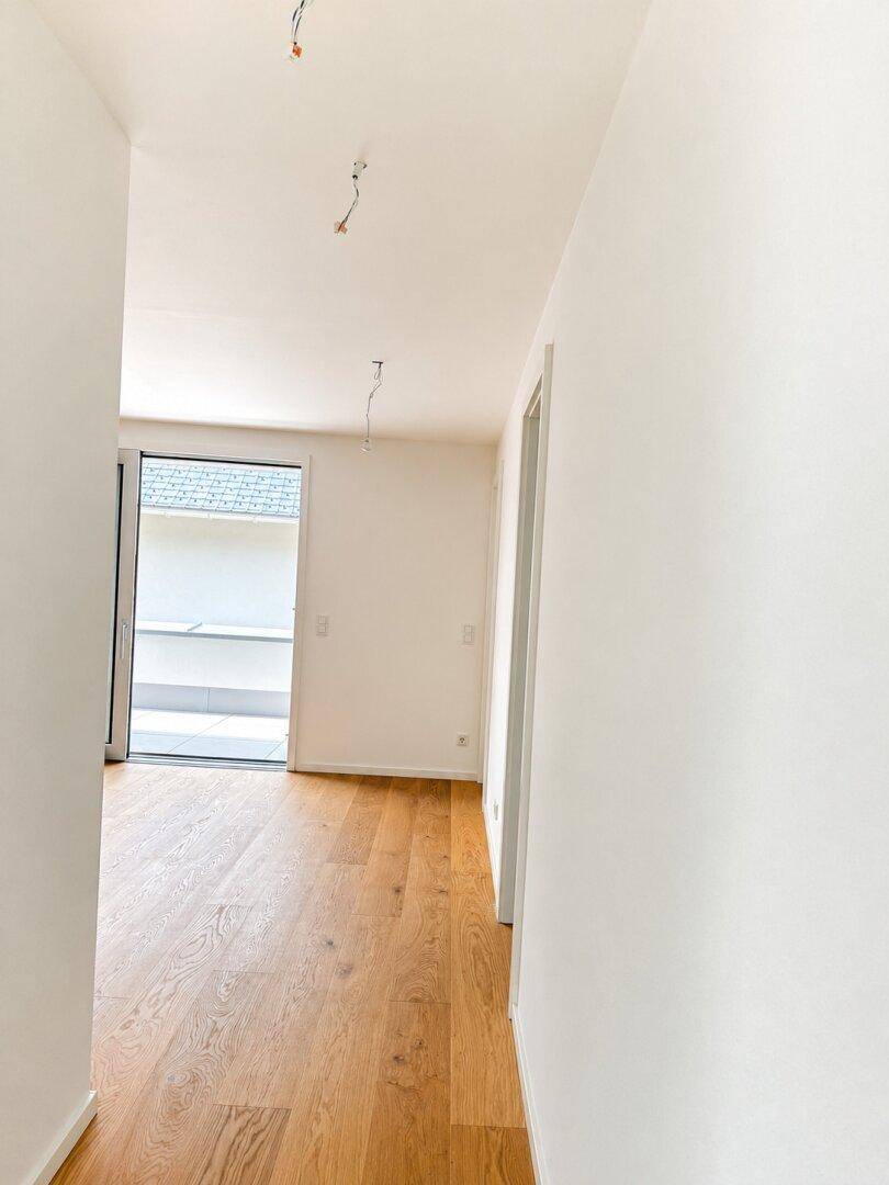 Lichtdurchfluteter Raum mit Eichenparkett und Zugang zu einem Balkon oder einer Terrasse.