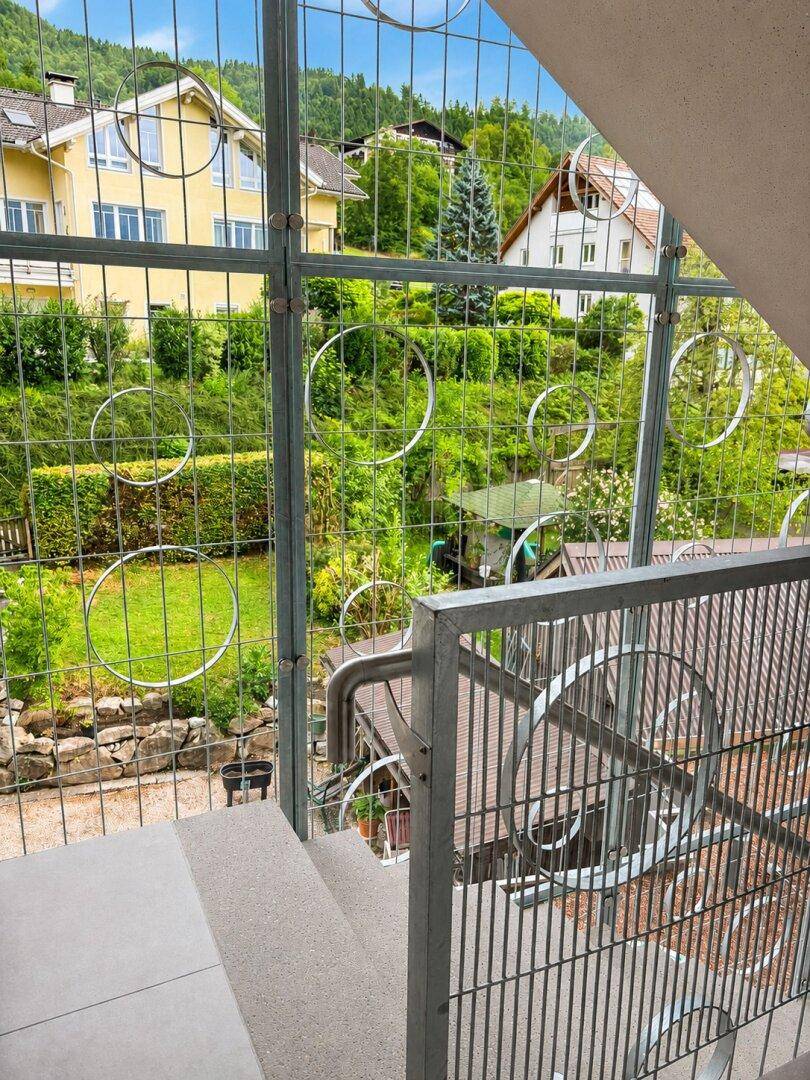 Außentreppe mit Metallgeländer und Blick auf einen gepflegten Gartenbereich.