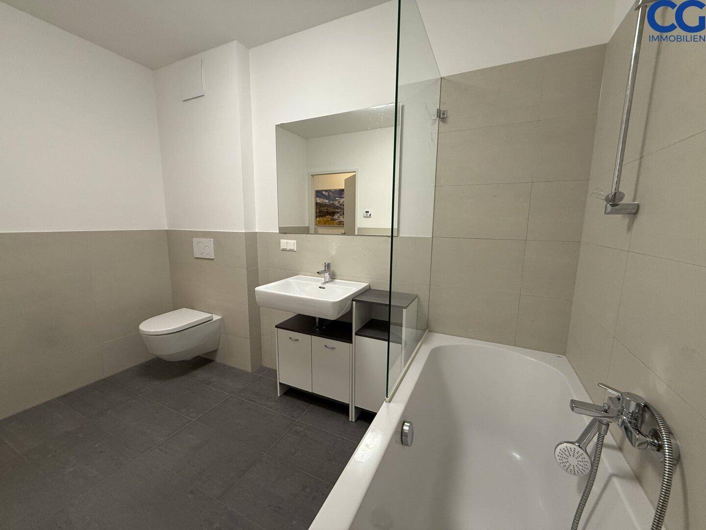 Modernes Badezimmer mit Badewanne, Duschbereich, wandhängendem WC und Waschtisch.