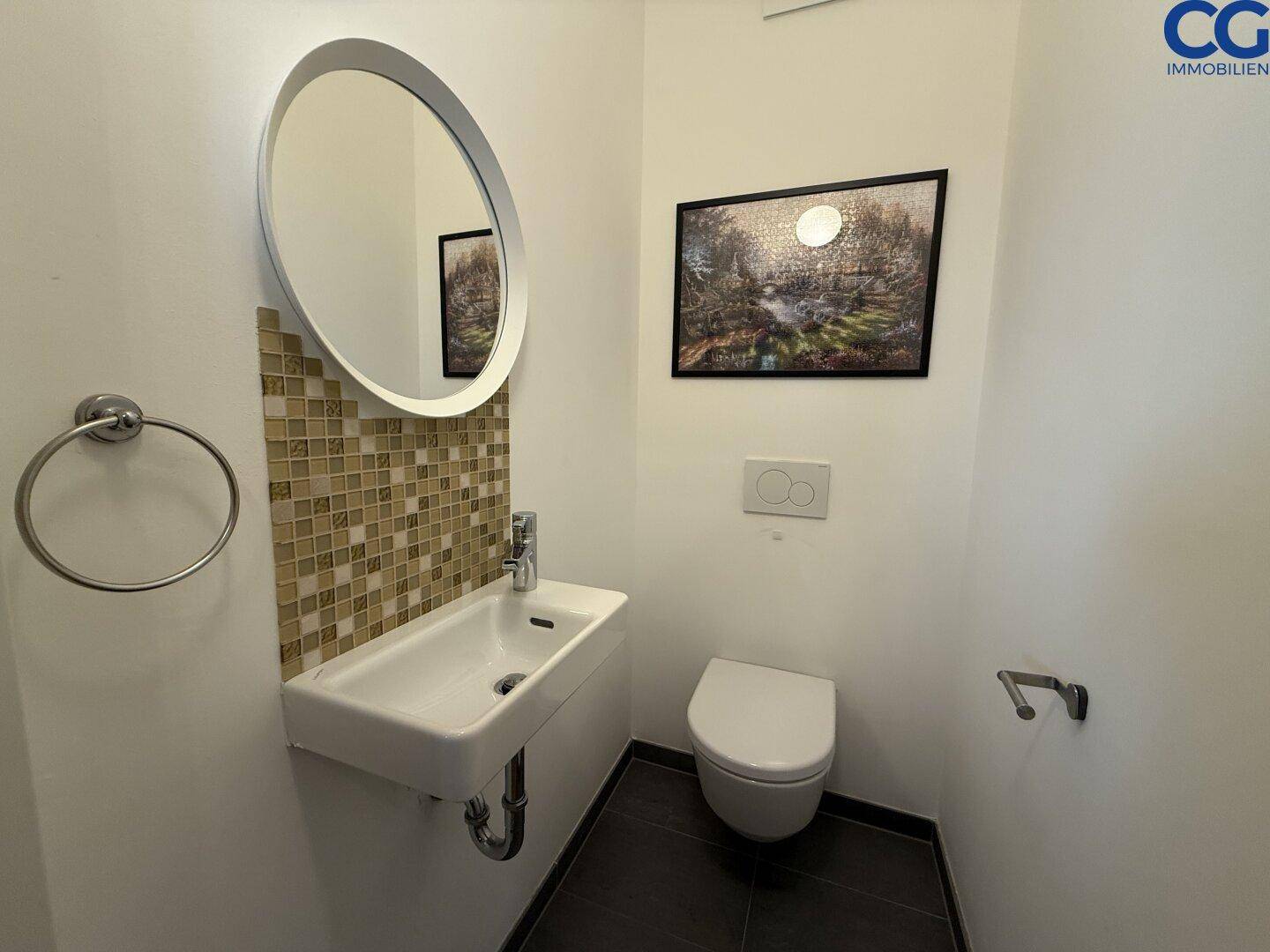 Modernes Gäste-WC mit Wand-WC, kleinem Waschbecken und dekorativen Mosaikfliesen.