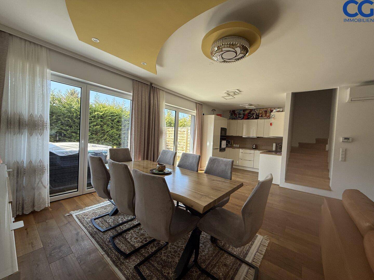 Geräumiger Essbereich mit Holztisch und Zugang zur Terrasse, angrenzend an eine moderne Küche.