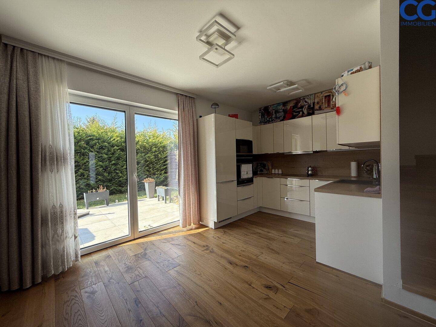Moderne Einbauküche mit weißen Schränken und Holzboden, mit direktem Zugang zur Terrasse.