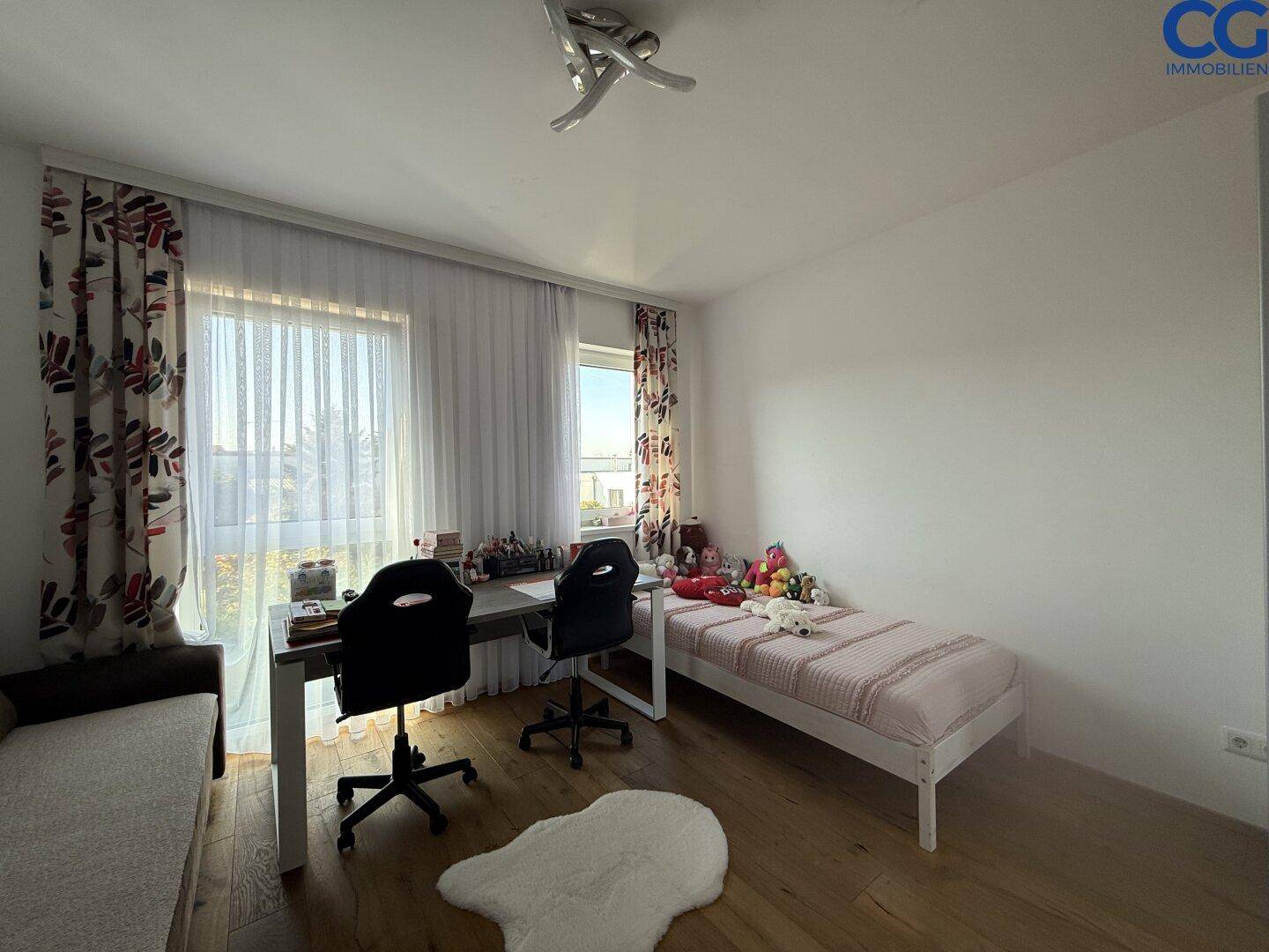 Helles Kinderzimmer mit Holzboden, Einzelbett und Schreibtisch am Fenster.