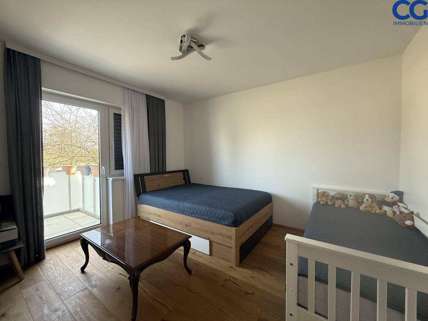 Schlafzimmer mit Holzboden und Zugang zu einem kleinen Balkon, ideal für Kinder.