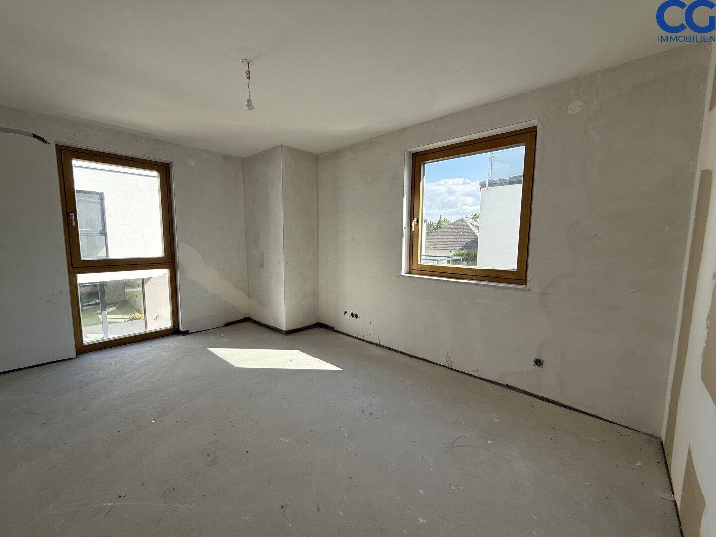 Unfertiges Schlafzimmer im Rohbau mit großem Fenster, bereit für den Innenausbau.