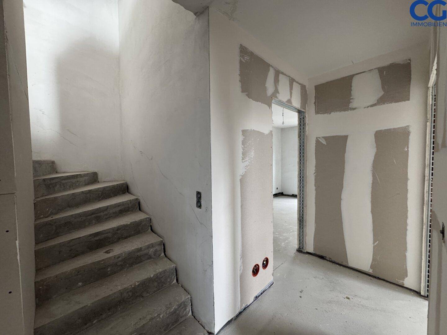 Treppenhaus und Flur im Rohbauzustand, bereit für die weitere Gestaltung und Fertigstellung.
