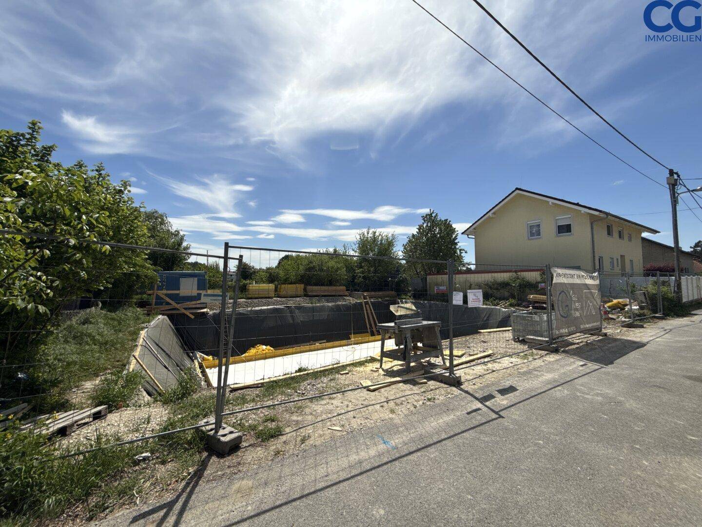 Übersicht der Baustelle mit Fundamentarbeiten und angrenzendem Wohnhaus.