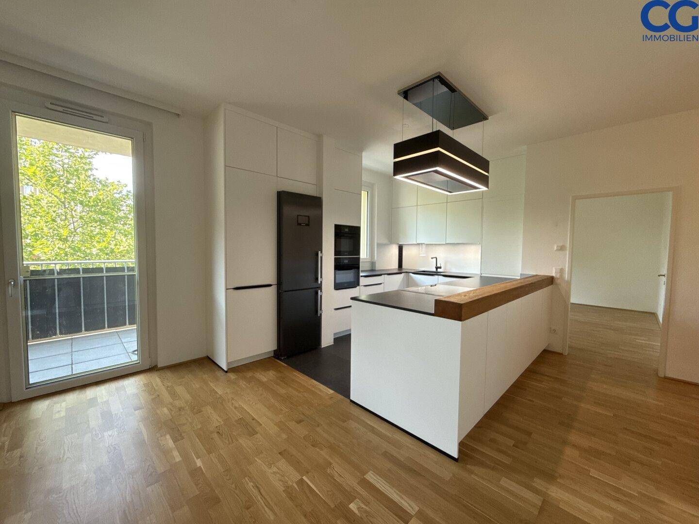 Moderne Küche mit weißen Schränken, schwarzem Kühlschrank und Kochinsel, mit Zugang zum Balkon.