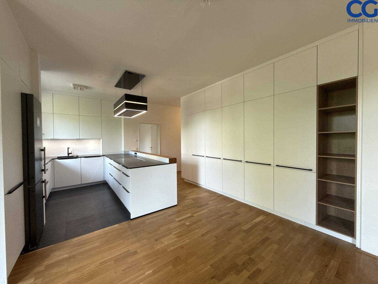 Geräumige moderne Küche mit weißen Einbauschränken, Kochinsel und integrierten Geräten.