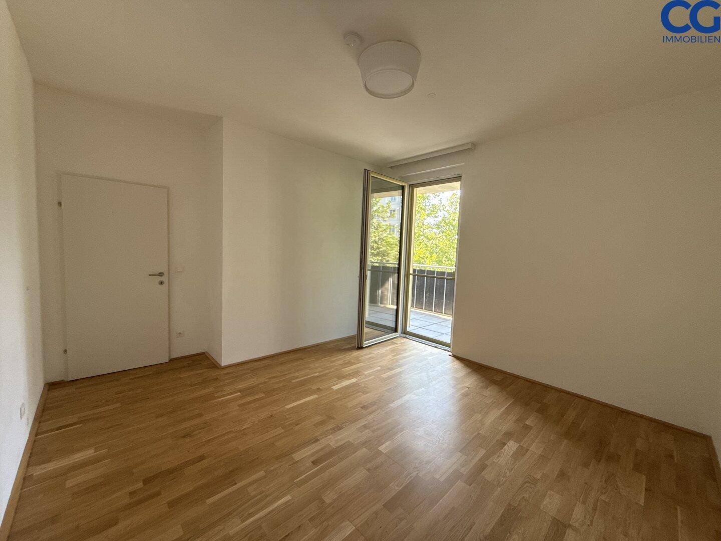 Helles Zimmer mit Holzboden und direktem Zugang zu einem Balkon, vielseitig nutzbar.
