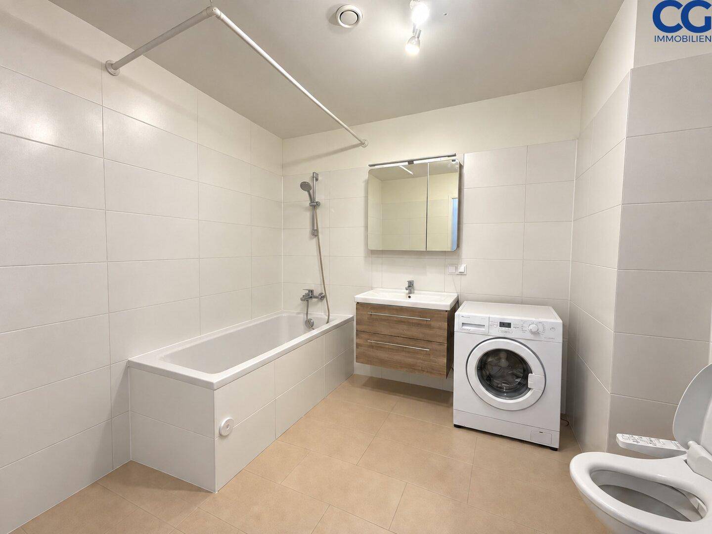 Geräumiges Badezimmer mit Badewanne, Waschbecken, WC und einer Waschmaschine.