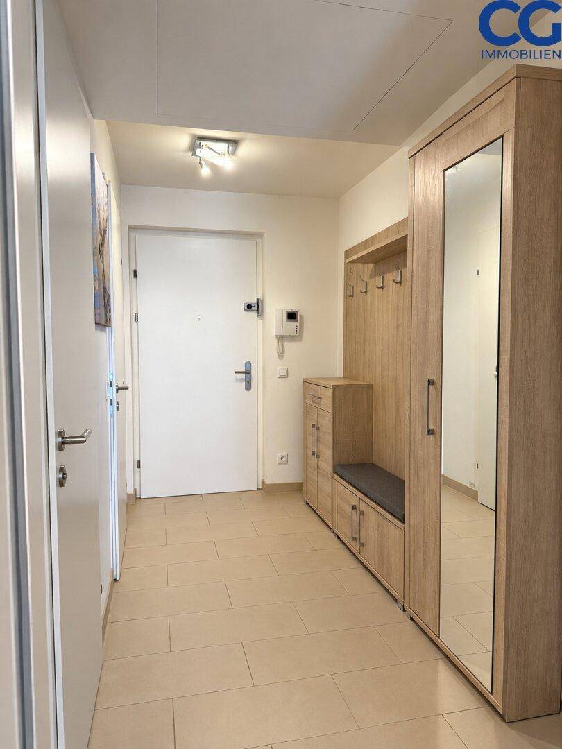 Heller Flur mit Fliesenboden und einem praktischen Garderobenschrank mit Spiegel.