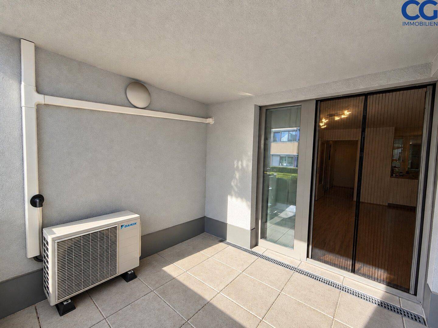 Überdachter Balkon mit Fliesenboden und installierter Klimaanlage.