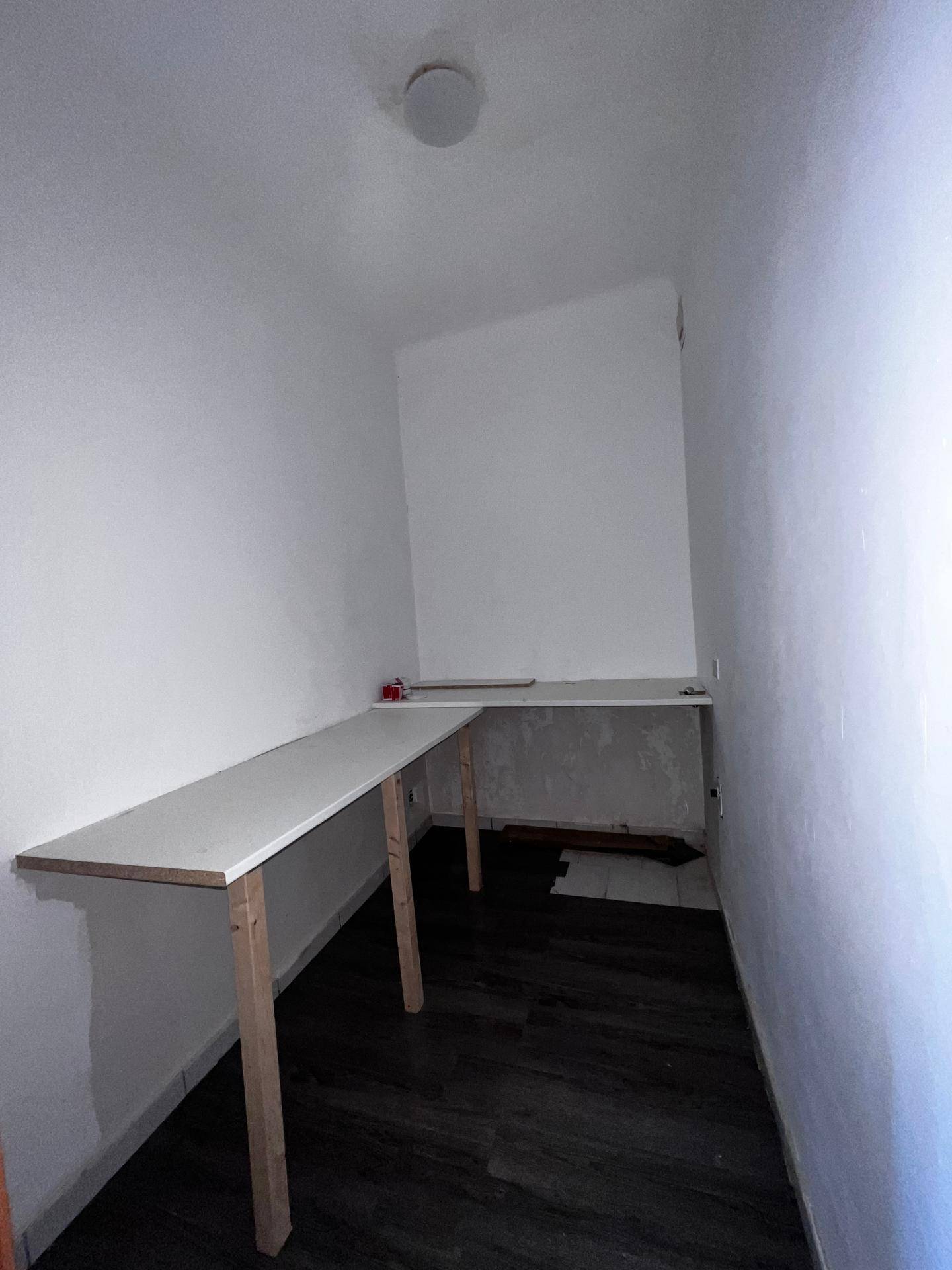 Praktischer Abstellraum mit Regalen und dunklem Boden, ideal für zusätzlichen Stauraum.