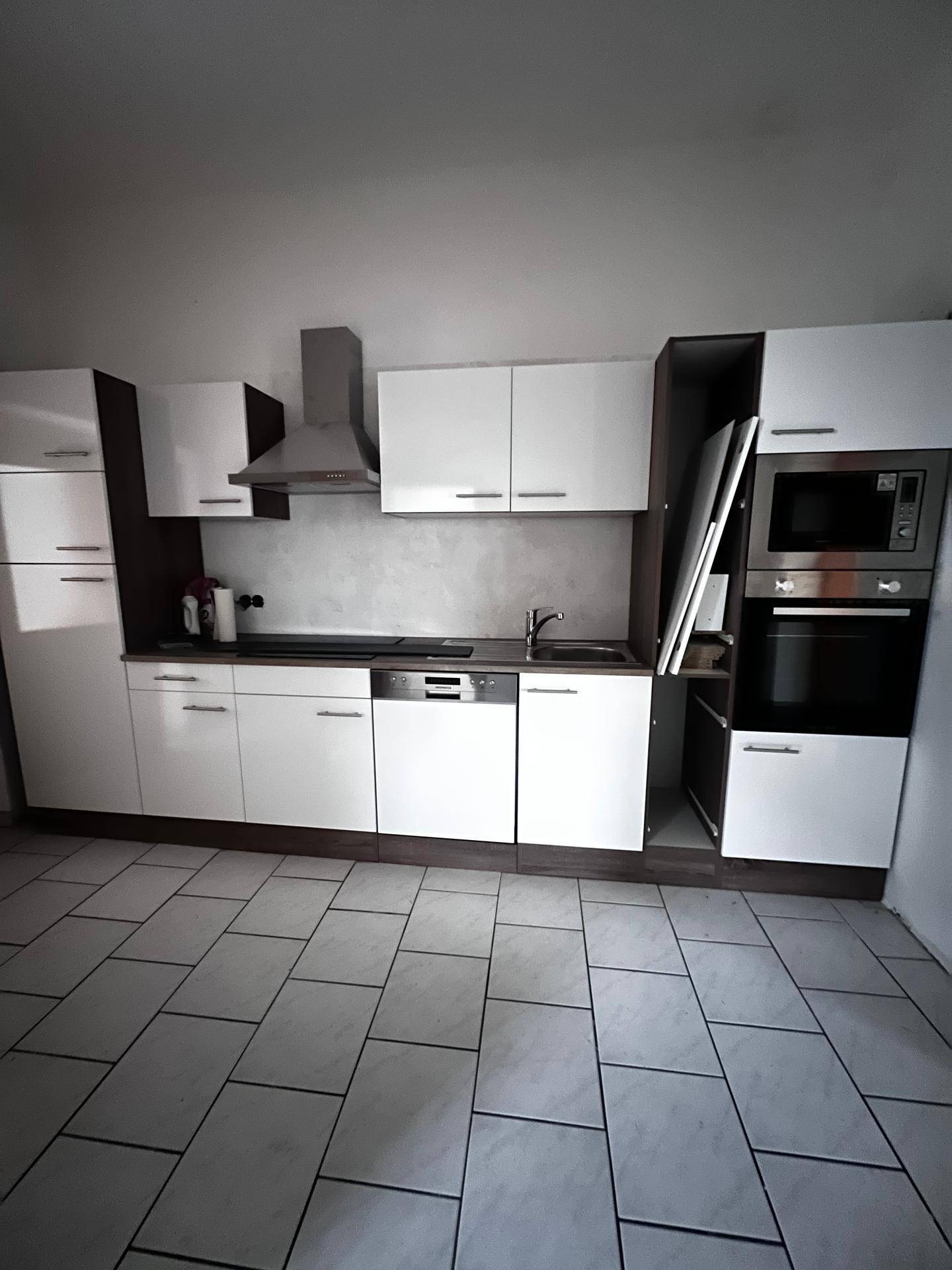 Moderne Einbauküche mit weißen Hochglanzfronten, integrierten Geräten und Dunstabzugshaube.