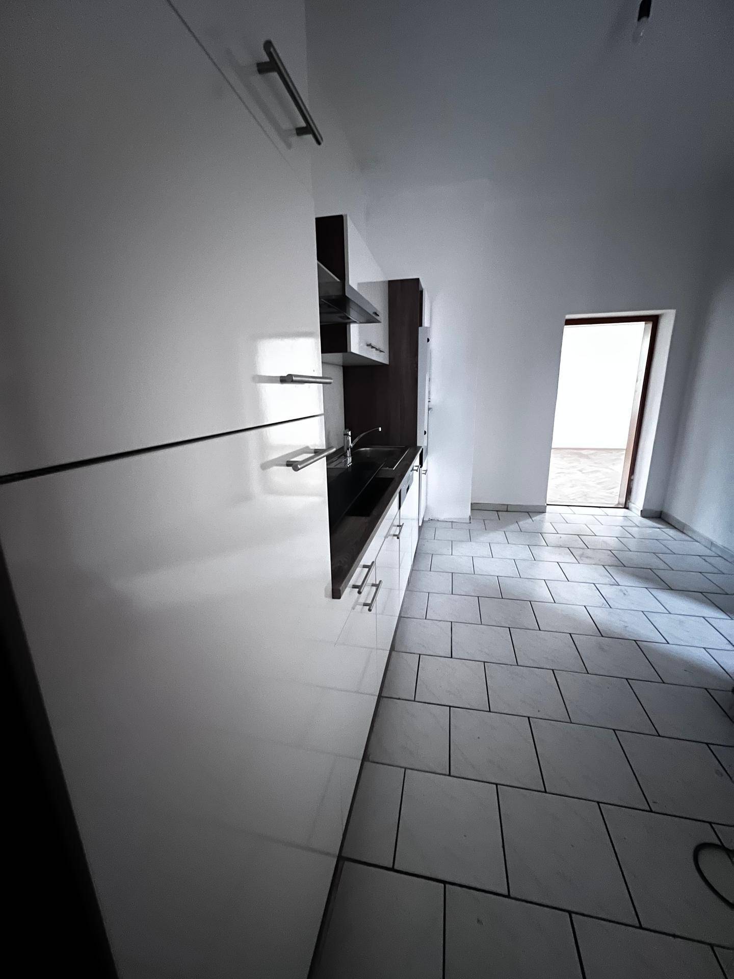 Schmale Küchenzeile mit weißen Schränken und dunkler Arbeitsplatte, ideal für kleine Räume.