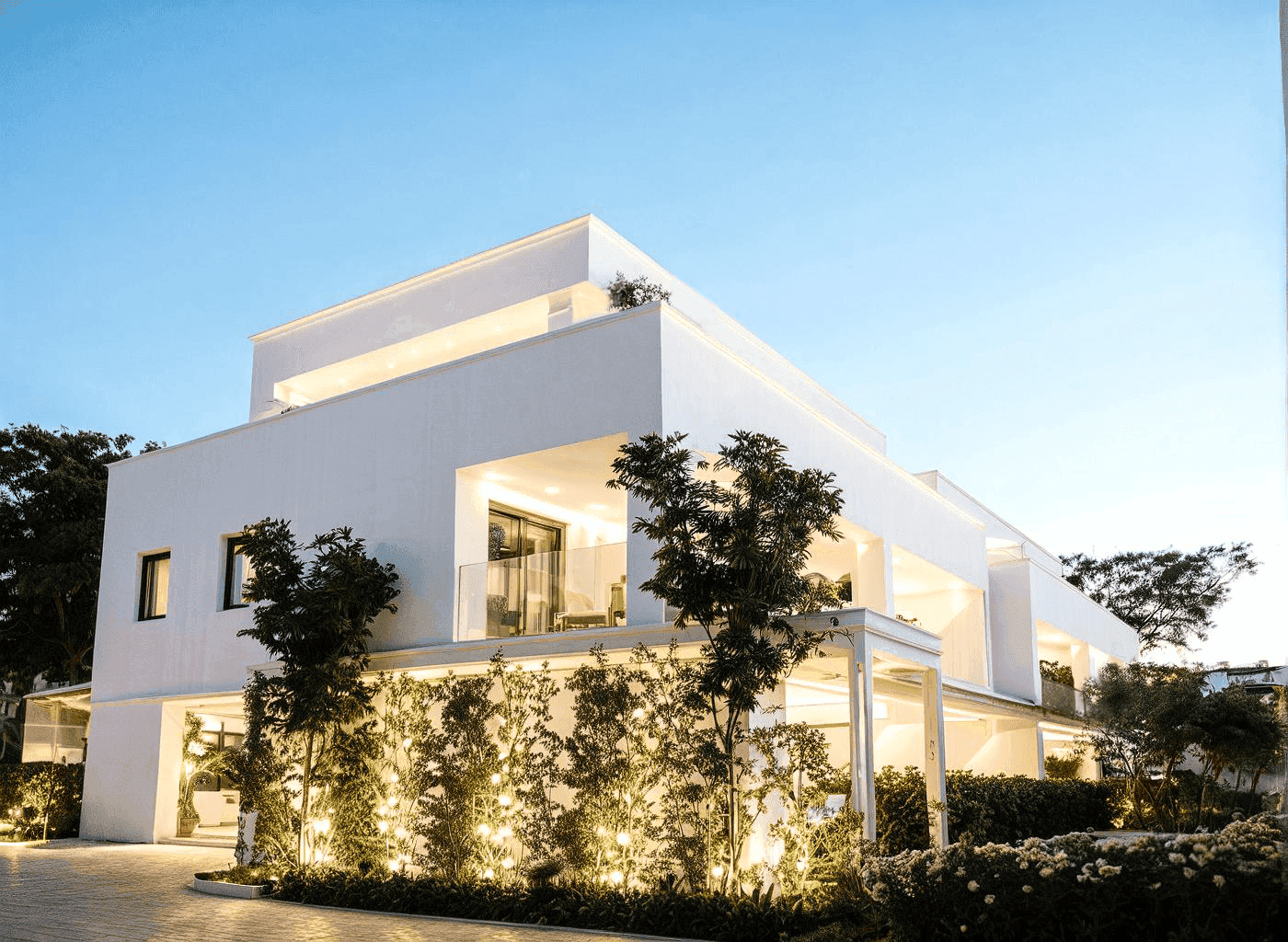 Elegante Wohnanlage mit moderner Architektur, beleuchteten Pflanzen und gepflegtem Eingangsbereich.