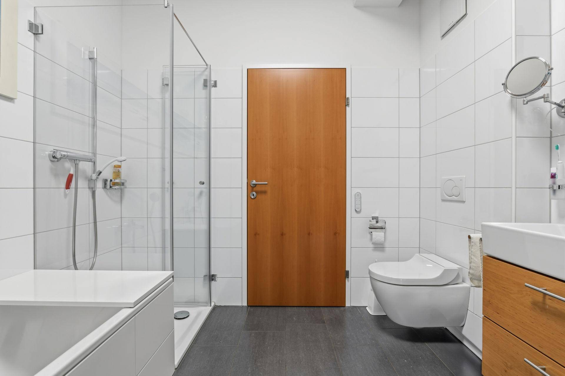 Modernes Badezimmer mit ebenerdiger Dusche, Wand-WC und stilvollem Waschtisch.
