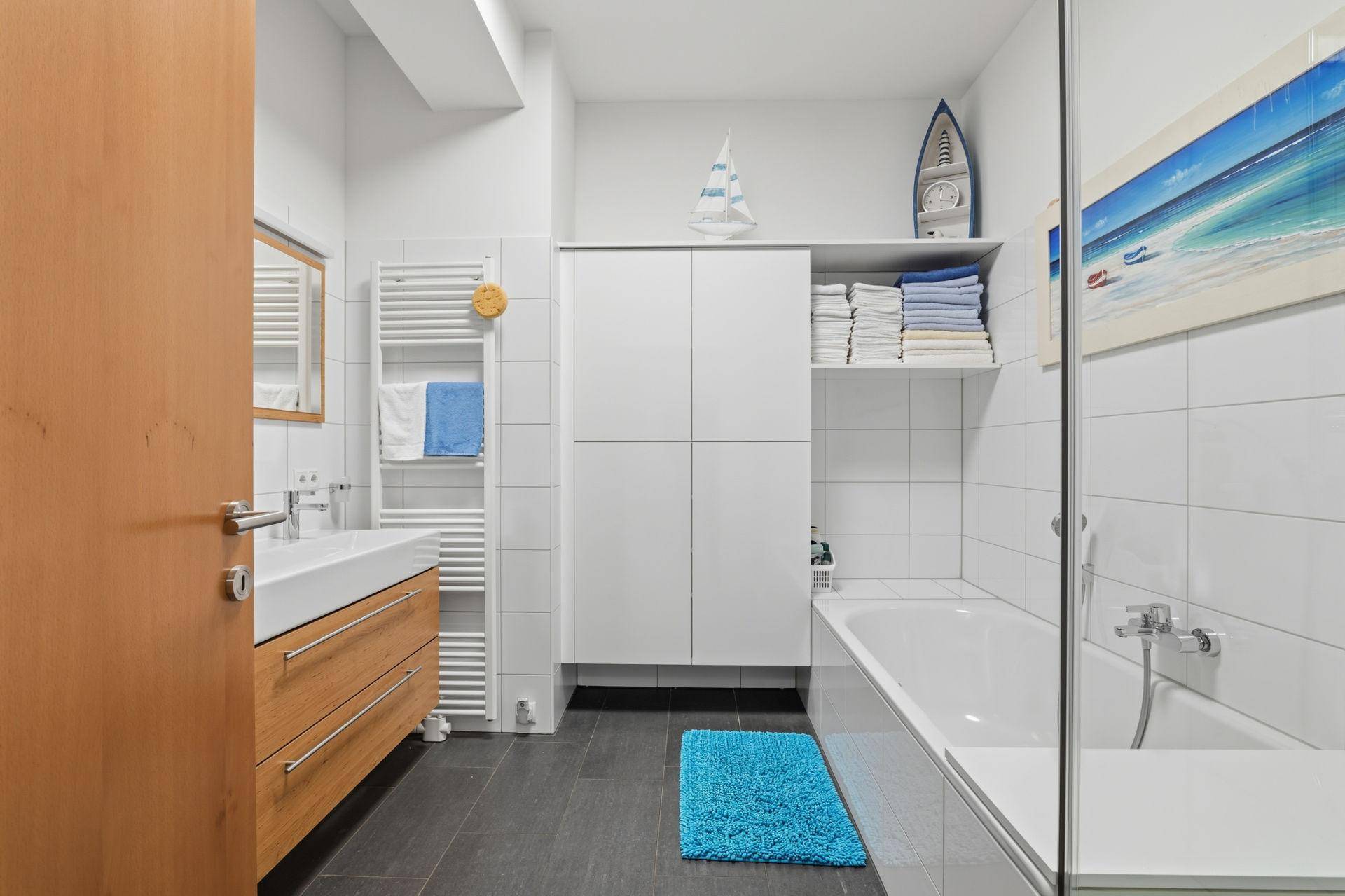 Modernes Badezimmer mit Badewanne, Holzwaschtisch und beheiztem Handtuchhalter.