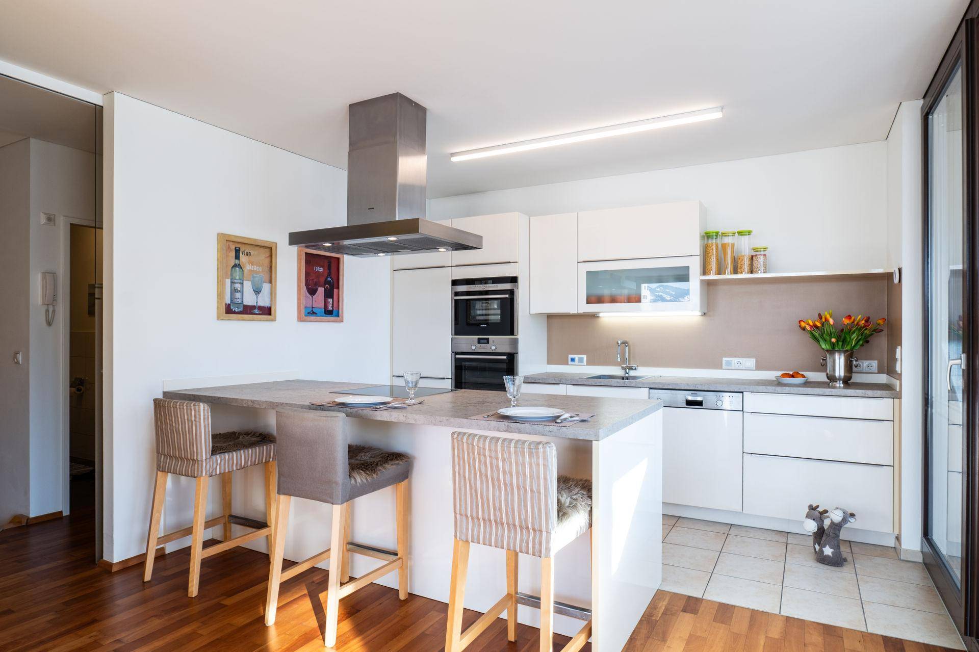 Moderne Einbauküche mit weißen Schränken, Kücheninsel und hochwertigen Geräten.