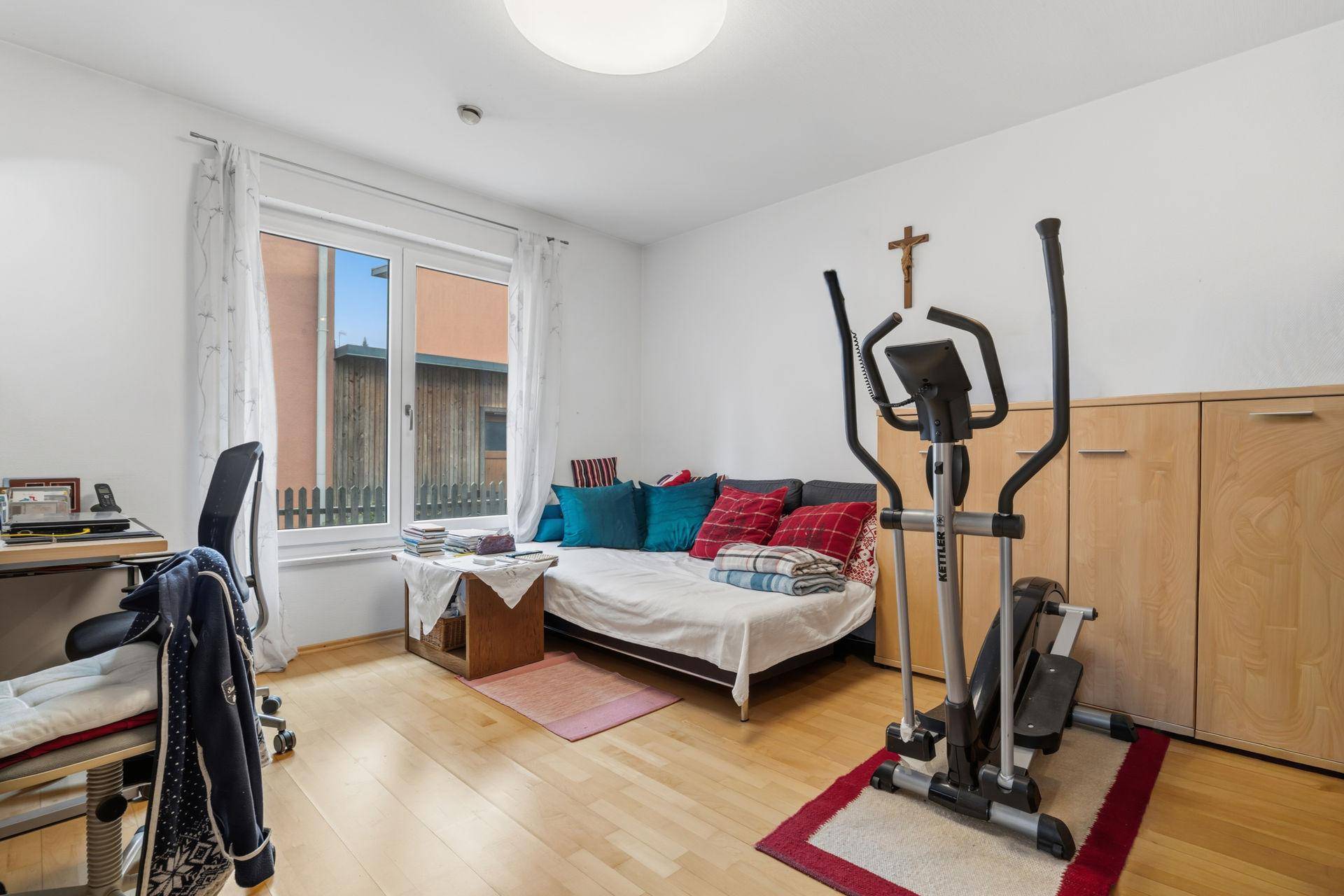 Multifunktionaler Raum mit Schreibtisch, Tagesbett und Fitnessgerät, ideal als Büro oder Gästezimmer.