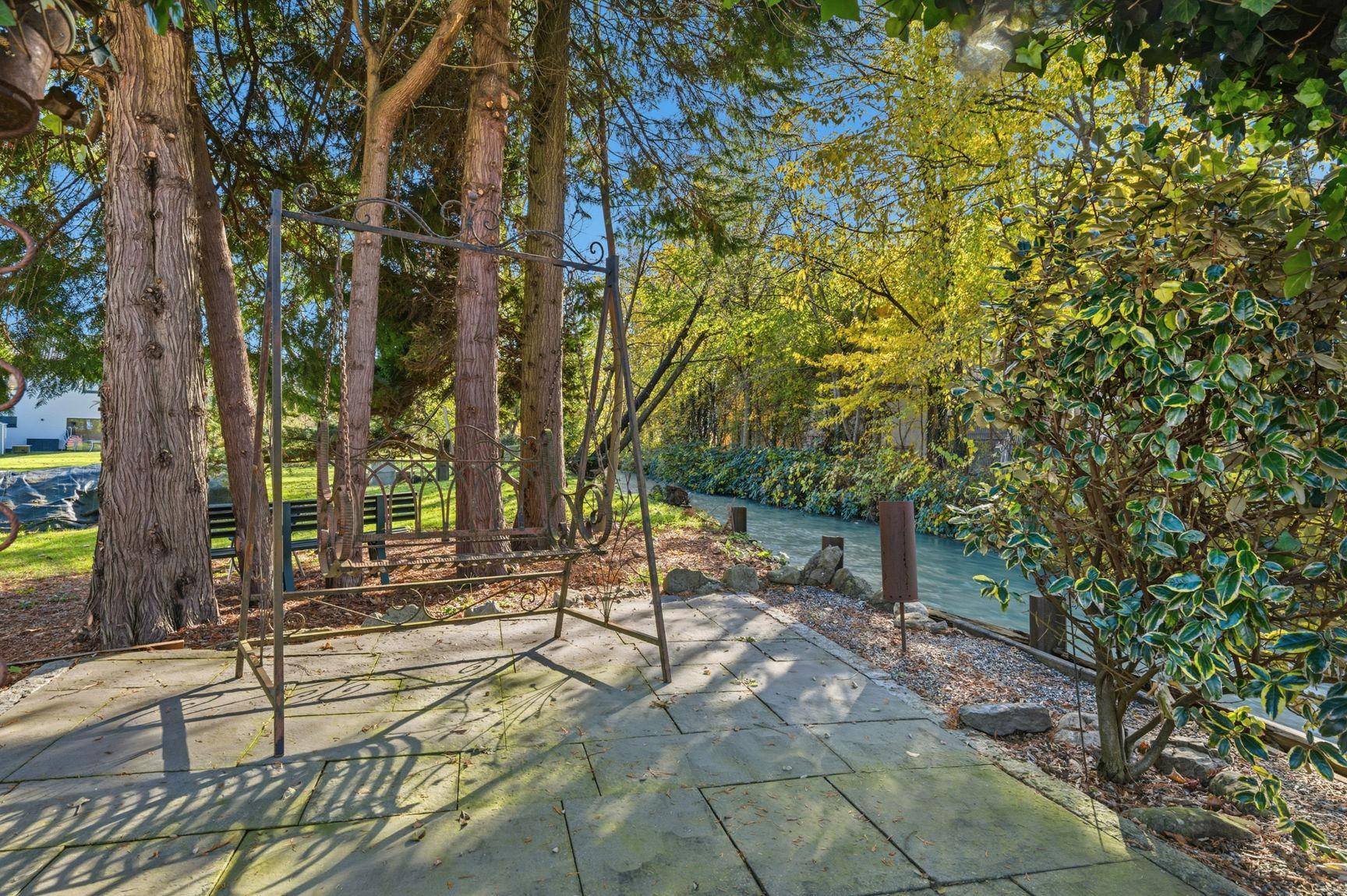 Idyllischer Gartenbereich mit alten Bäumen, Schaukelbank und direktem Zugang zum Flussufer, sehr ruhig.