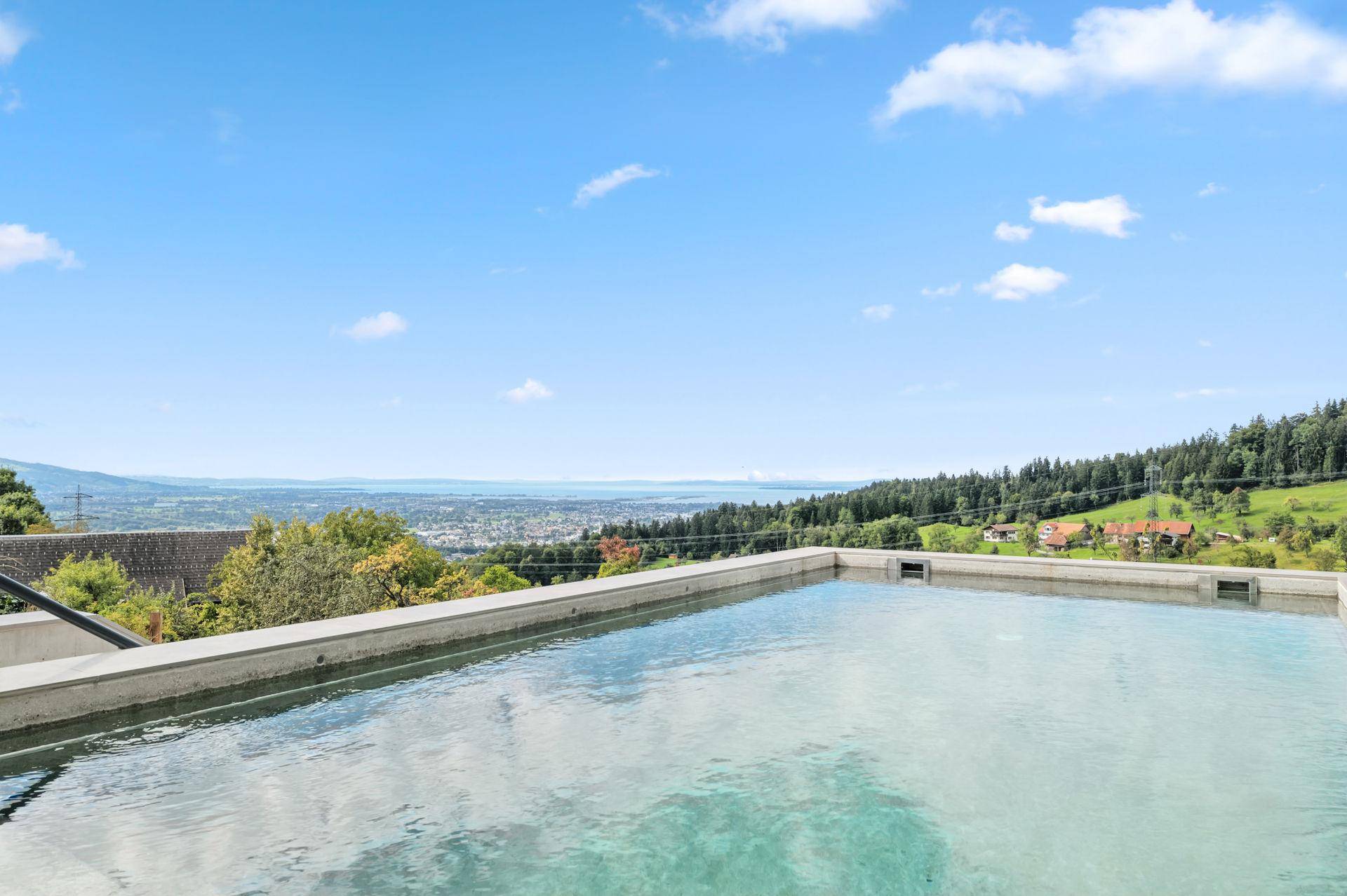 Außenpool mit Panoramablick auf den fernen See, die Stadt und die grüne Landschaft.
